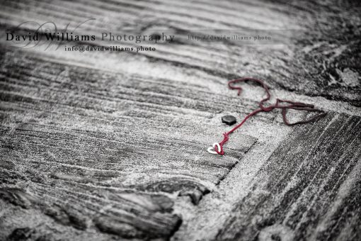 A heart on a string forgotten on a sandy boardwalk in California.